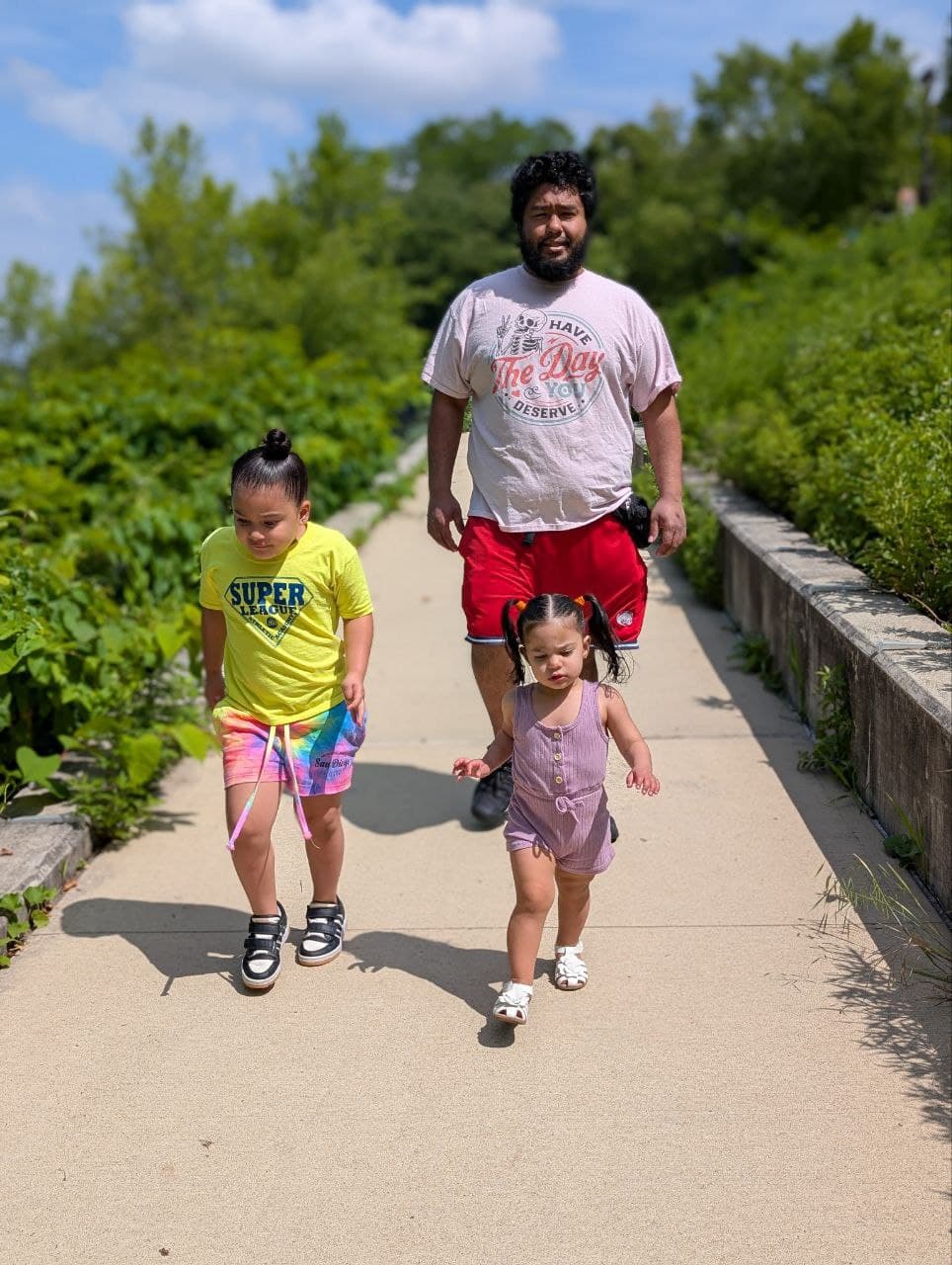 Rizbe walking with his two children on a sunny path